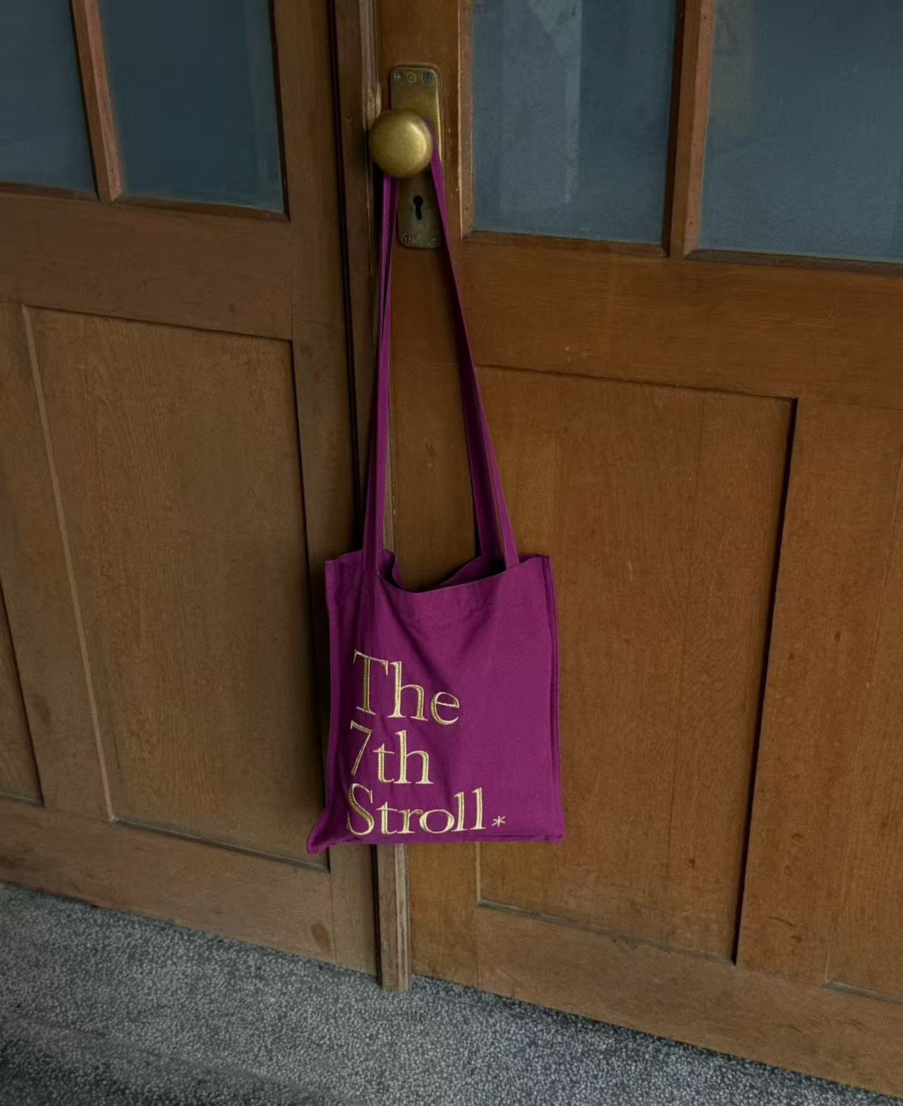 The 7th Stroll 紫色托特包掛在木門上